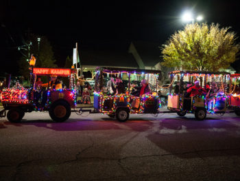 Christmas parade; tractor pulling carts covered in lights